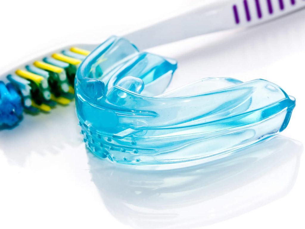 photo of blue mouth guard next to toothbrush