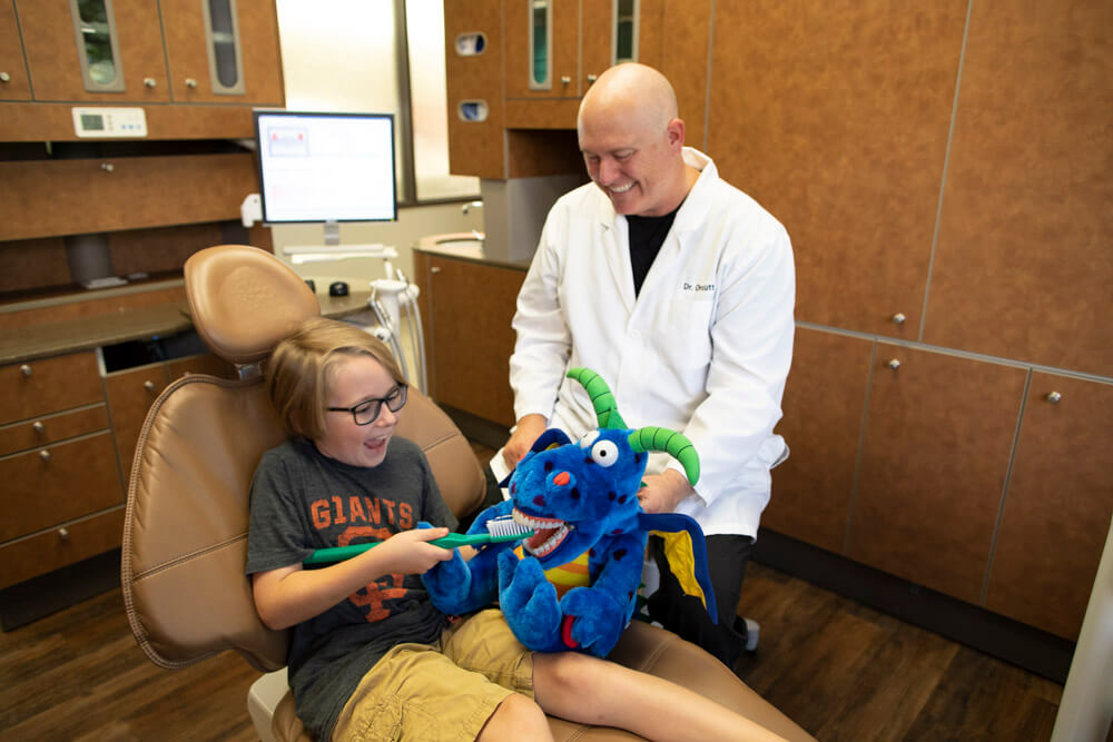Dr. Brian Orcutt of Orcutt Family Dentistry in Fair Oaks CA helping child in dentist chair brush stuffed animals teeth